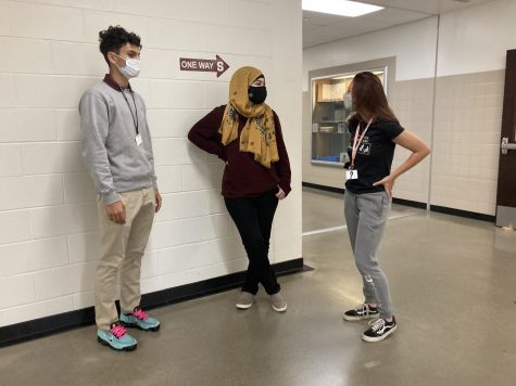 Three stroudsburg students engaging in mask-covered conversation.
