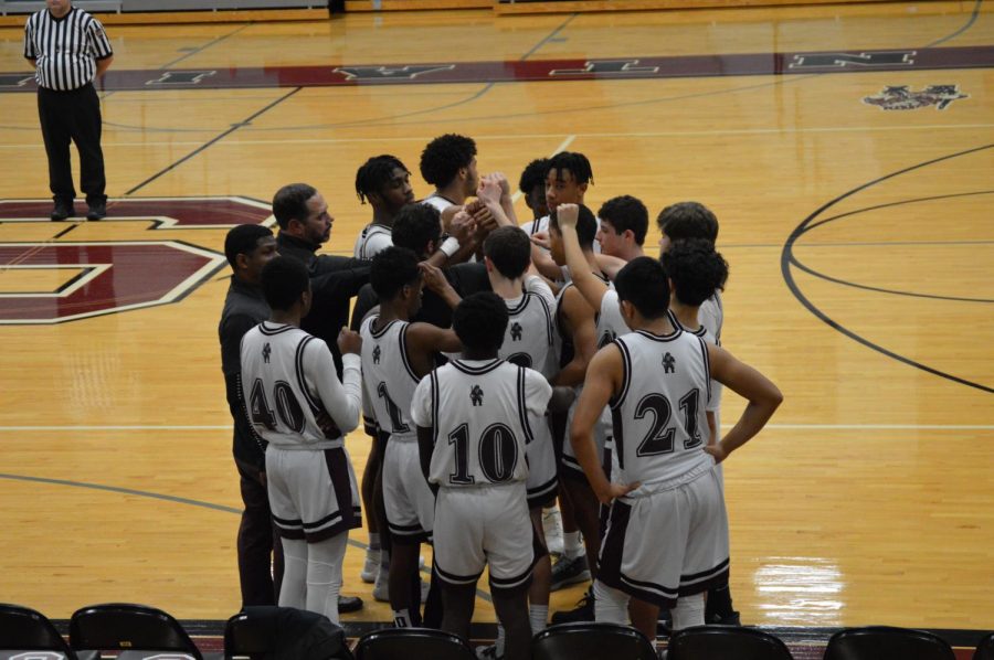 The boys JV basketball team come together during a timeout in a 2020 contest.
