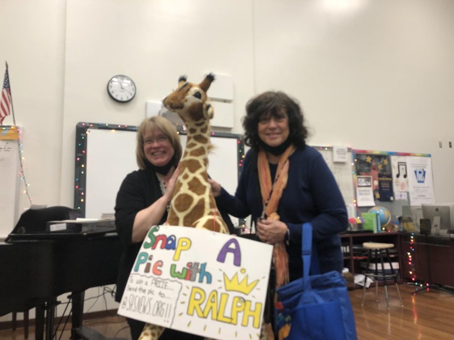 SHS staff members pose with Ralph the giraffe in the chorus room.