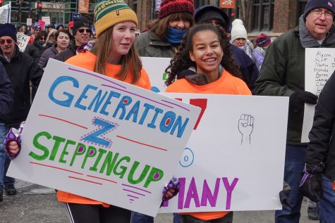 A girl attending a rally holds a sign that reads Generation Z Stepping Up.