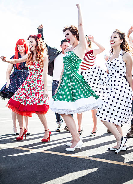 Friends (group) dancing and laughing and smiling outside on a sunny day in fifties style clothing - stock image