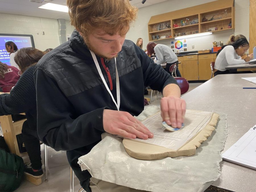  This student uses sculpting techniques to complete his relief plate. (Erin Mazol) 