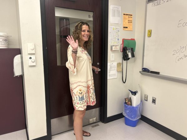 Ms. Lobasso poses at the door of her classroom, waving goodbye to her students.