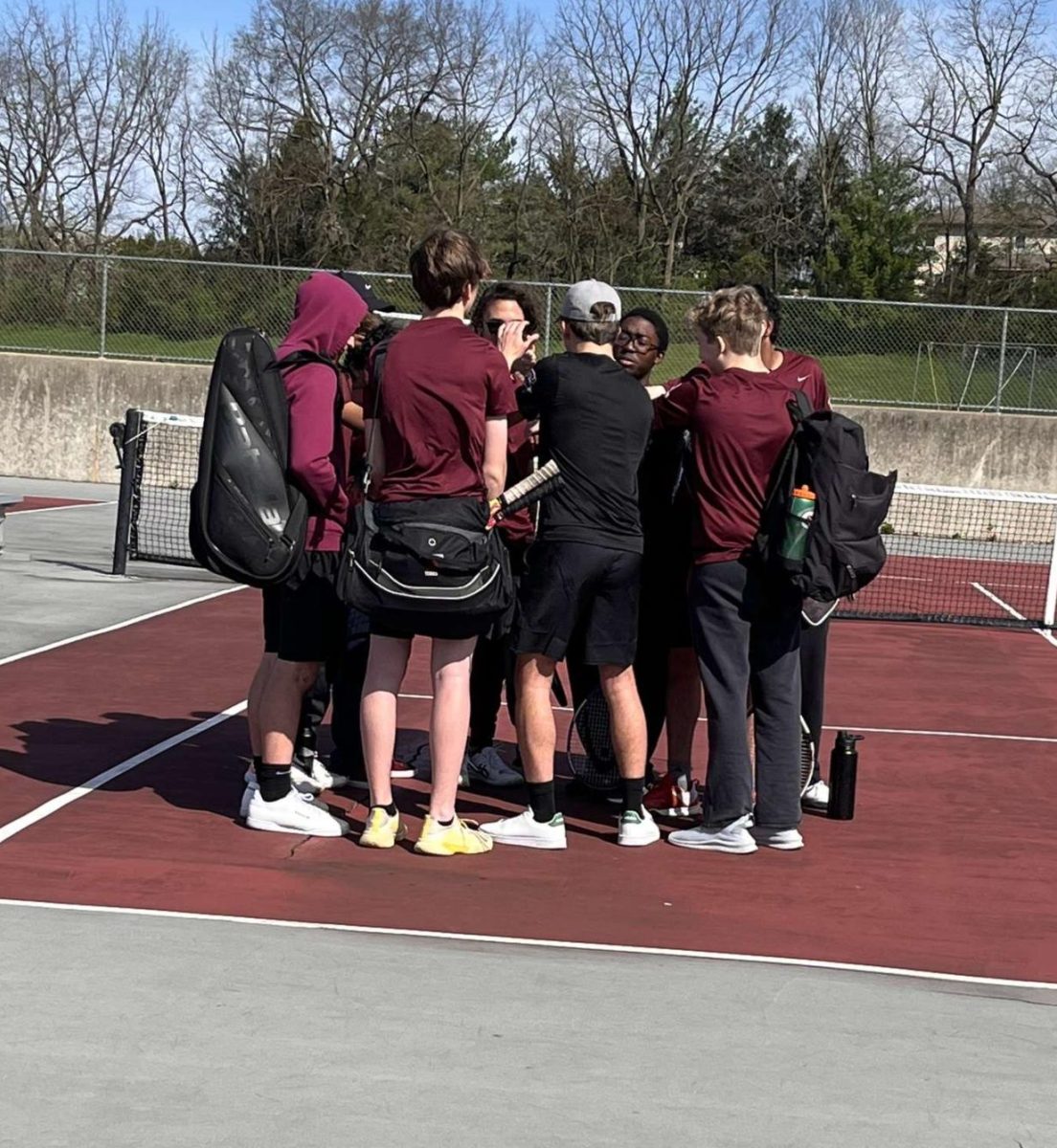 Boys tennis regroups in a huddle. 