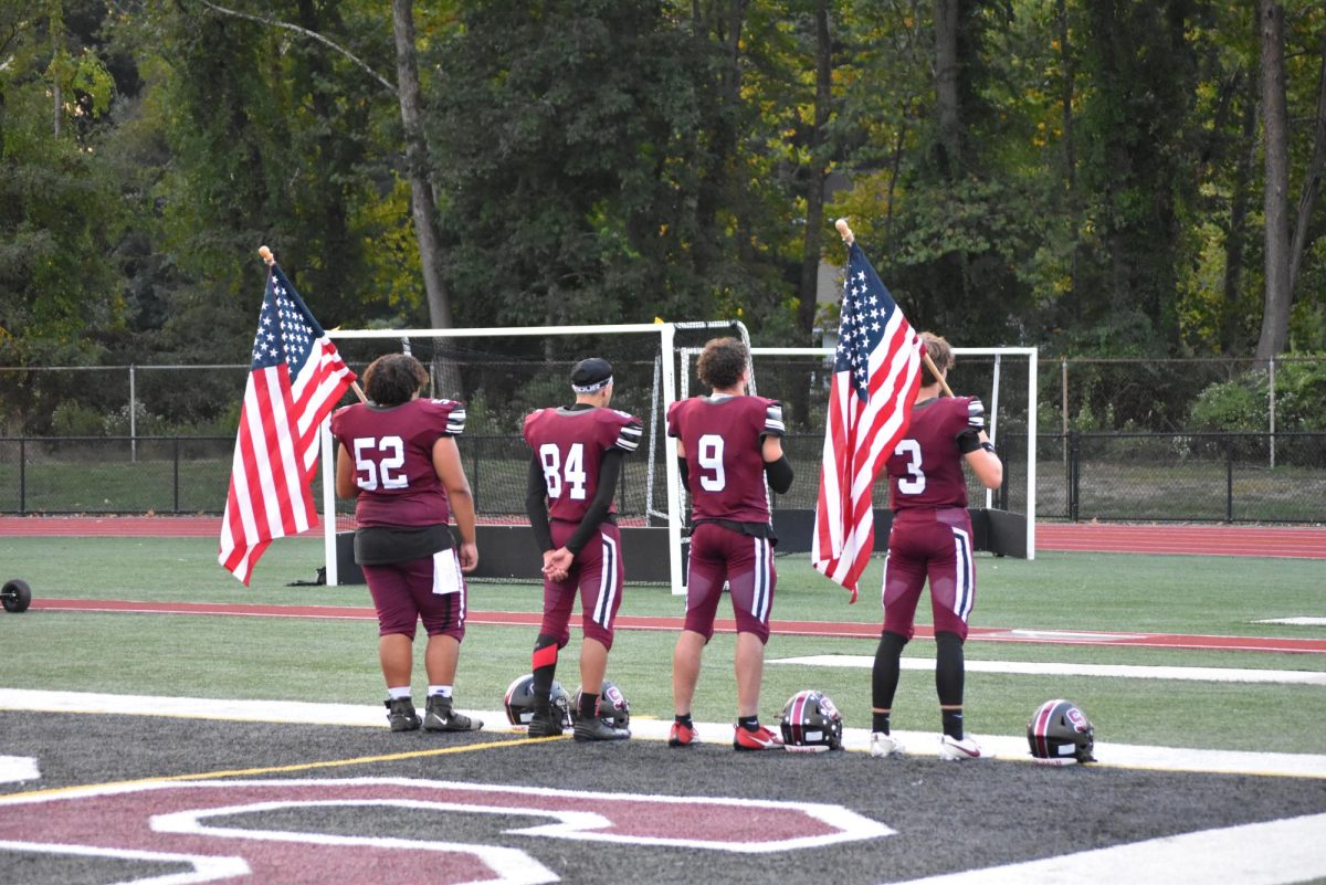 Football captains Emaunel Laboy, Ethan Dudsak, Karis Wilkins, and Ben Pilcher line up during the National Anthem on September 13, 2024.