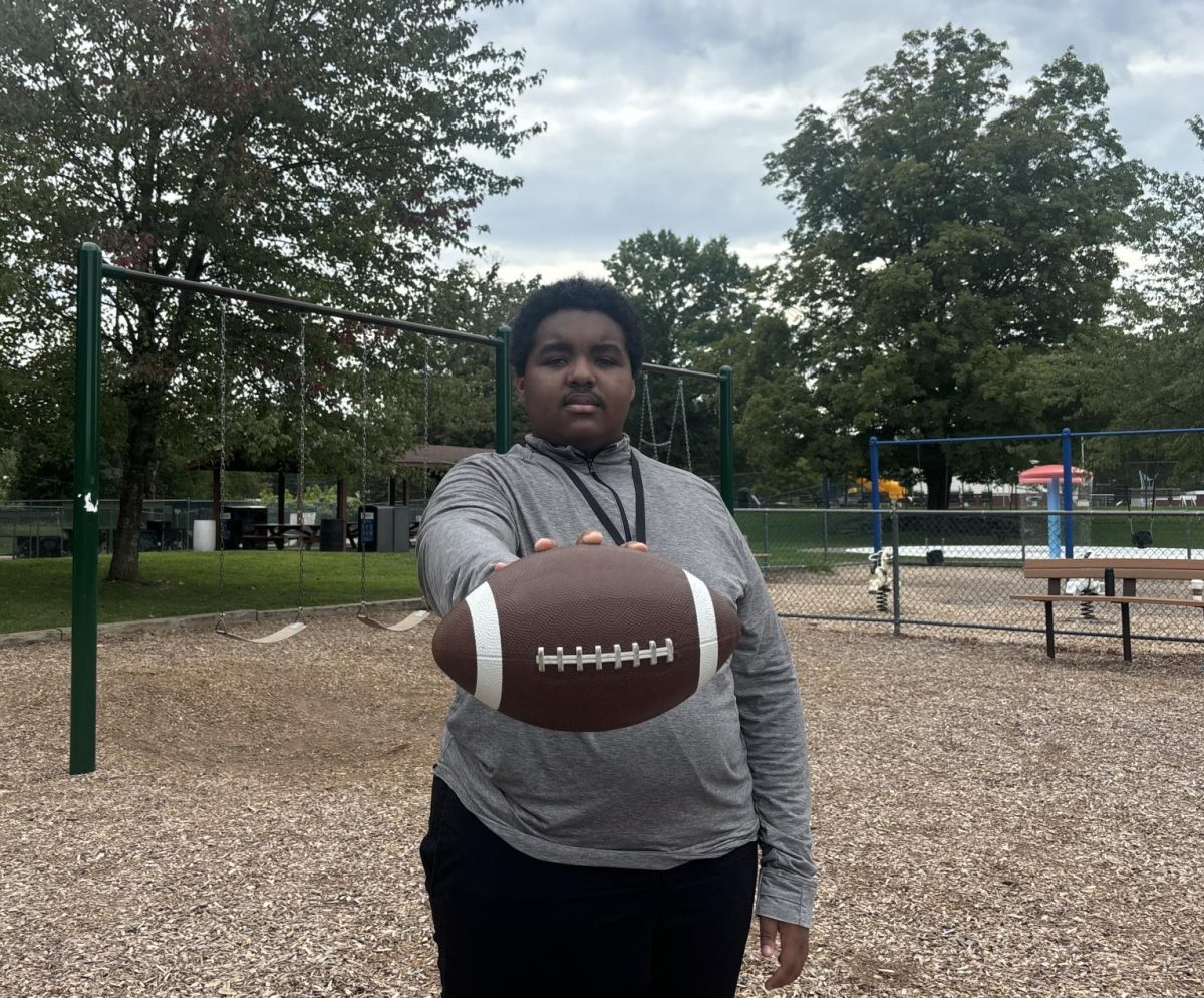 Sport Editor Jaden Harper, '25, posing for a picture with a football. 