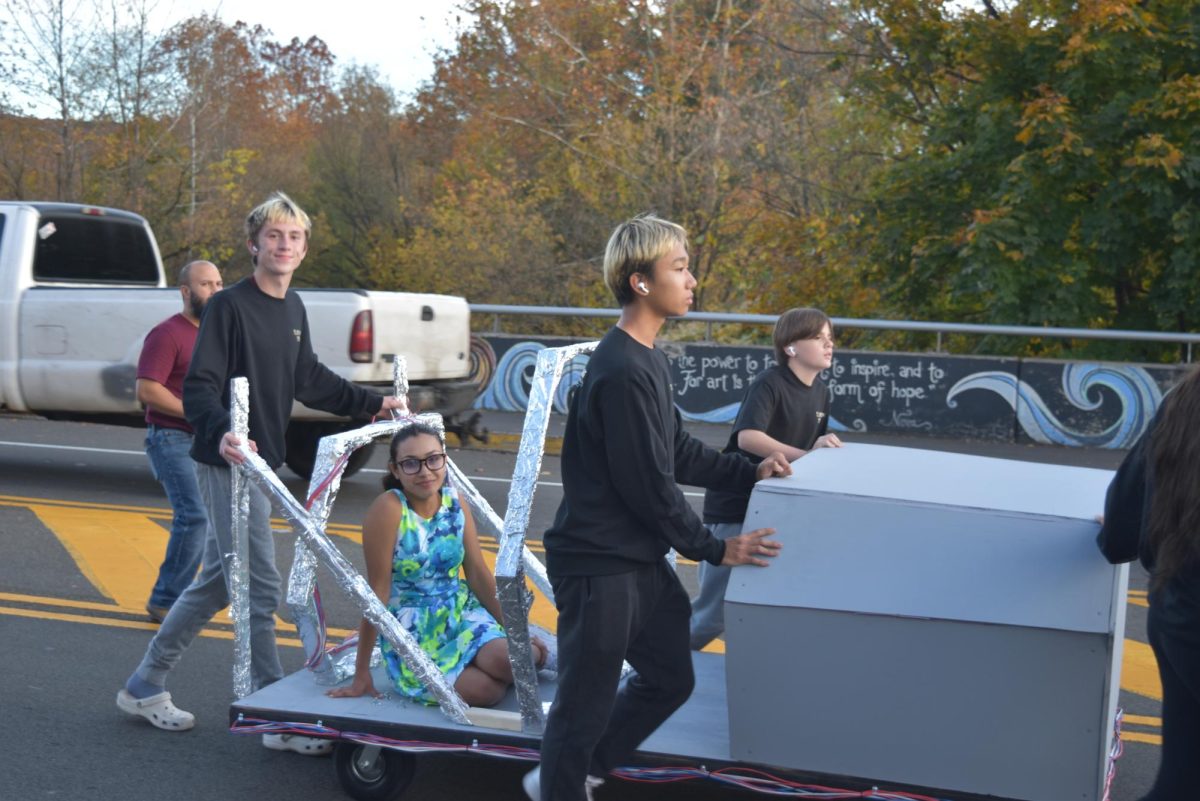 Andrew Paxton, '27, James Lee, '27, Isabella Rivera, '26, and Reagan Scelza, '27 walk with their model of the ¨Back to the Future¨ time car. 