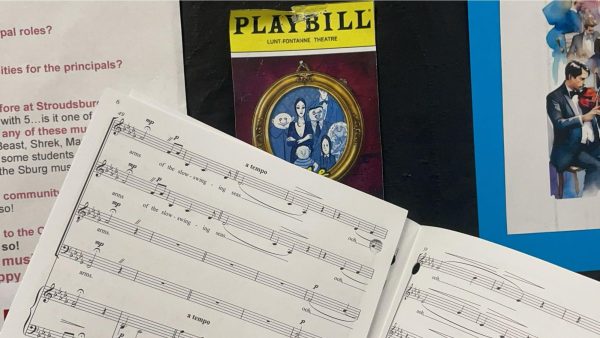 Music held up next to the playbill of "The Addams Family." 