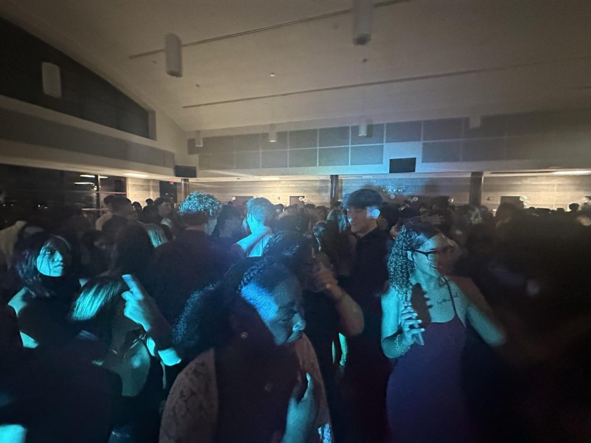 Students dancing in the cafeteria while being illuminated by blue lights. 