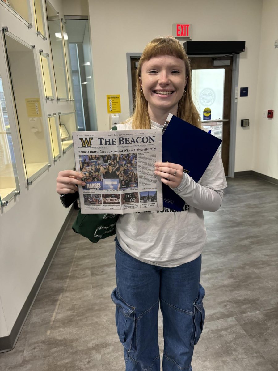 Crista Kopec posing with the Wilkes newspaper with the front page being Kamala Harris