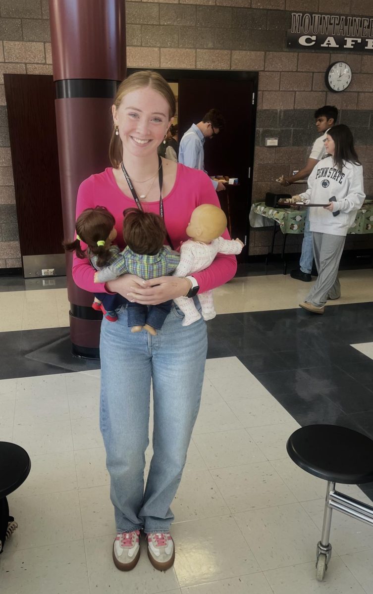 Grace Coyne '26, dressed up as an adult holding three babies during Dress Your Age.