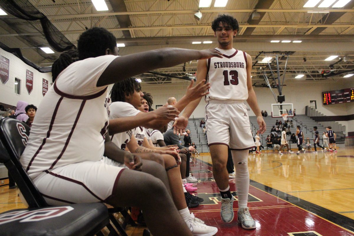 The boys basketball team praises Essam Alrefai, '26, as he is taken off the court.