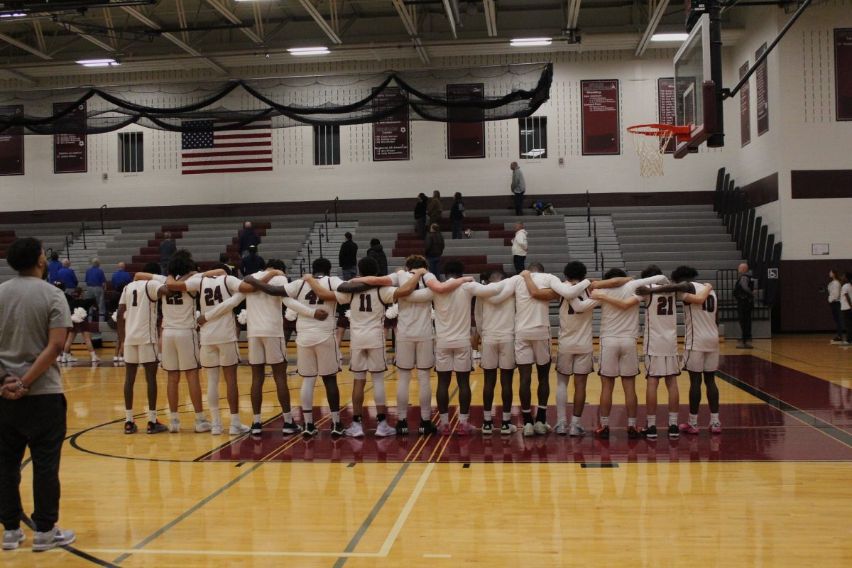 The boys basketball team pay their respects during the National Anthem.