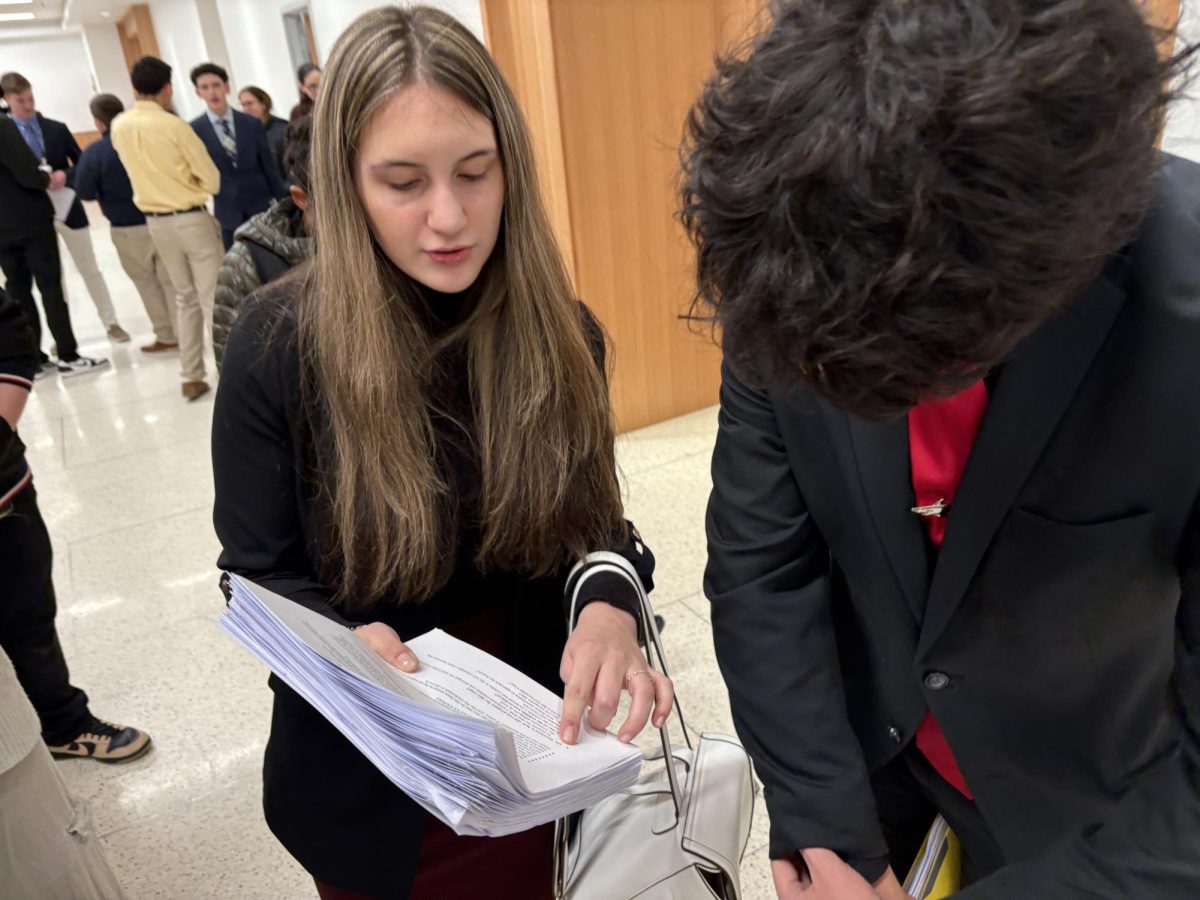 Aryanna Vidaic, '26, looking over papers and discussing the case with her team member.