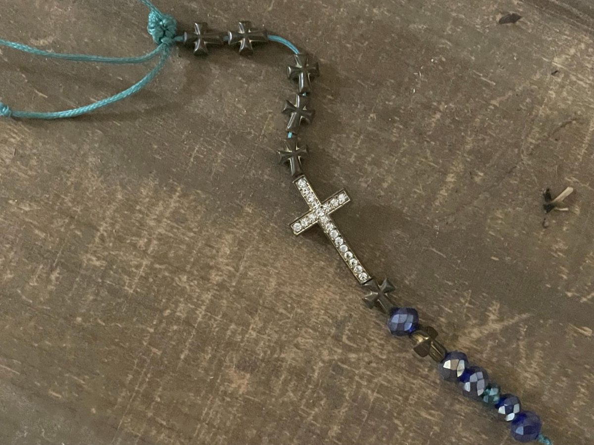 A picture of the cross on a key chain against a wooden background. 