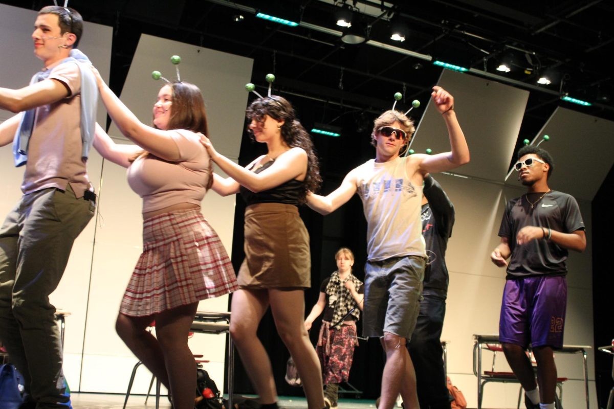 Sophia Nieves, '26, Olivia Celano, '25, and Ben Pilcher, '25, in a conga line at the end of the show. 
