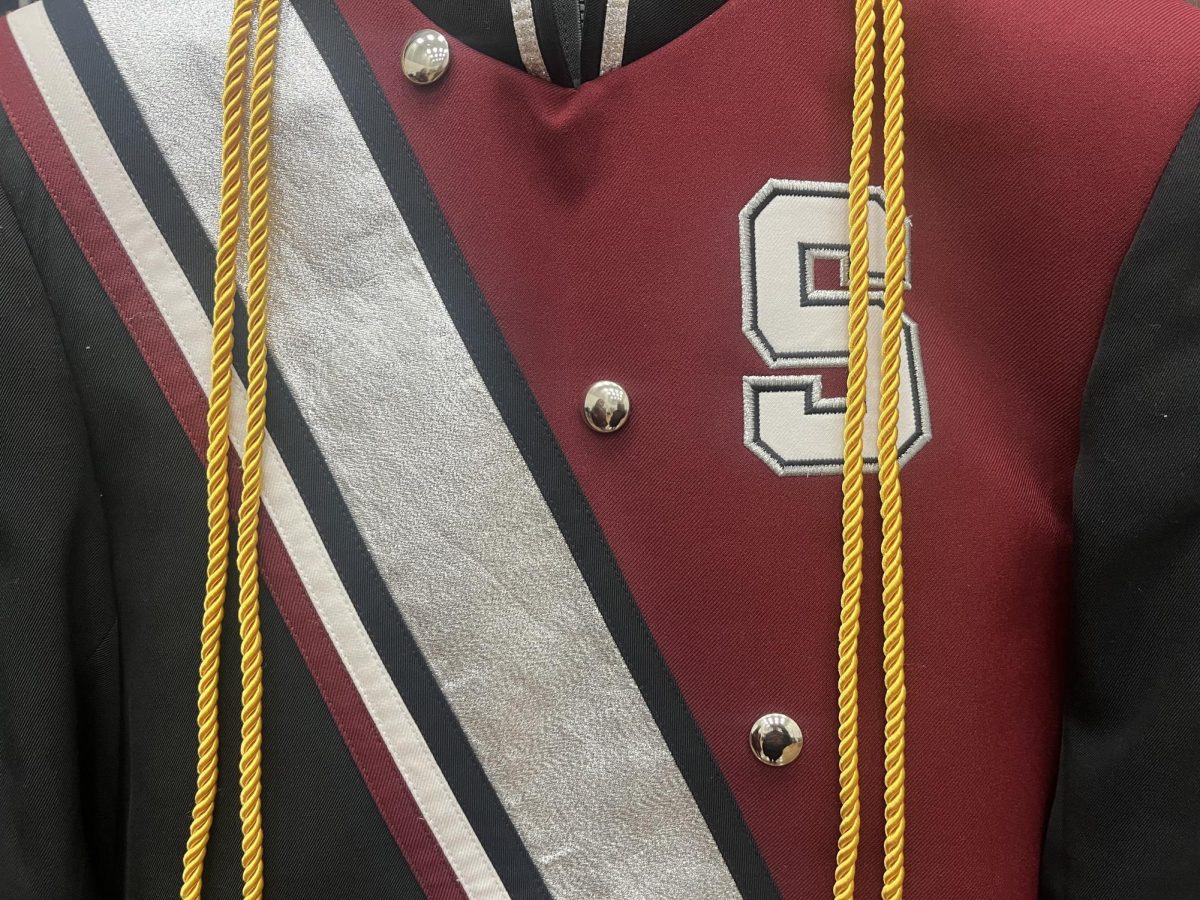 A picture of the marching band uniform with a graduation cord around it.