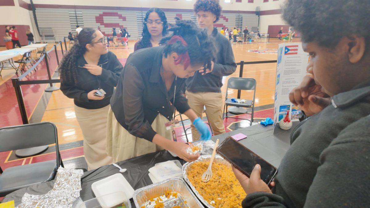 Kaleb Gareld '27 patiently waiting as Karen Chapman '27 puts traditional Puerto rican Rice on a plate.